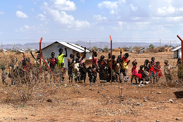A group of curious kids cling to a fence as staff from the non-governmental organization Center for Victims of Torture tour their healing center in Kakuma Refugee Camp, located in the northwestern region of Kenya. Photo courtesy of: Fawn Bernhardt-Norvell